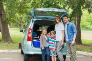 Family standing in front of a car