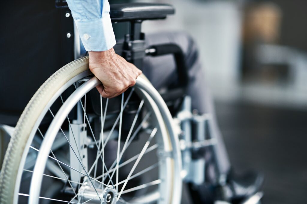 a wheelchair, with the wheel being grabbed by the person sitting in it